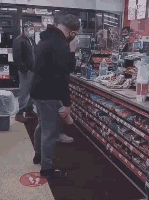 a man wearing a mask is standing in front of a counter in a store