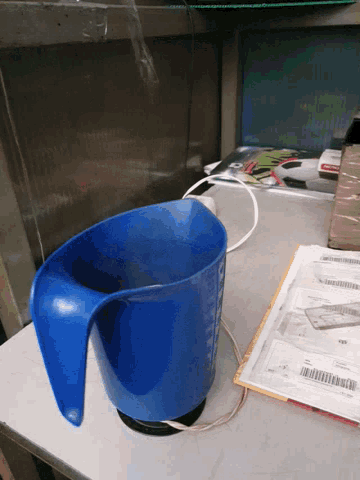 a blue measuring cup sits on a table next to a book that says ' aa ' on it