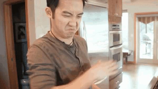 a man making a funny face in front of a stainless steel refrigerator
