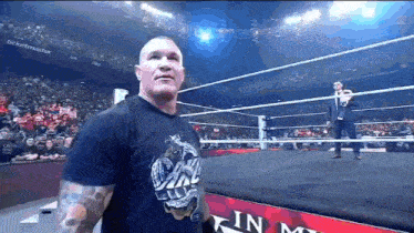 a man in a black shirt stands in a wrestling ring with a sign that says in my