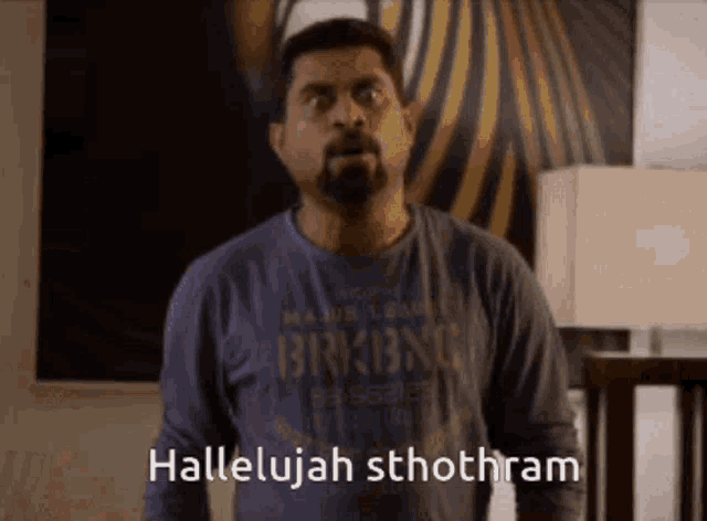 a man with a beard wearing a blue shirt that says hallelujah sthothram