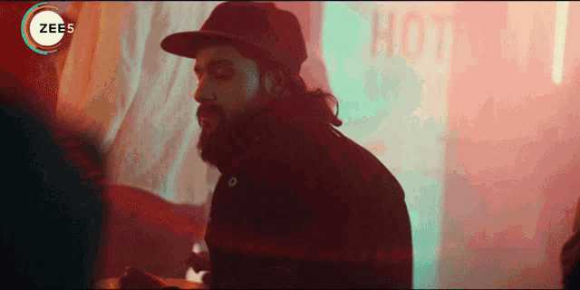 a man with a beard is standing in front of a sign that says " hot "