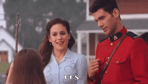 a man in a red uniform is talking to a woman in a blue shirt .