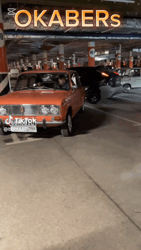 a red car is parked in a parking garage with a sign that says okabers