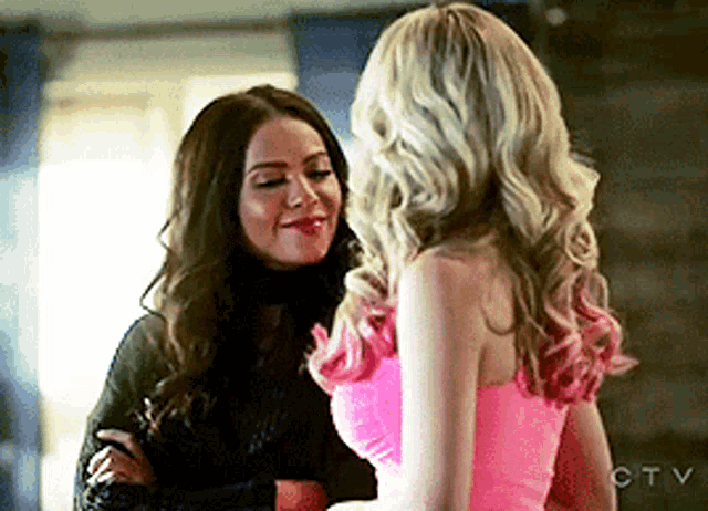 two women are standing next to each other and one is wearing a pink dress
