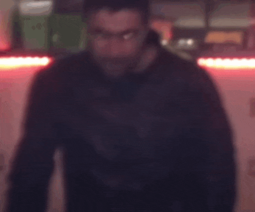 a blurry picture of a man in a suit and tie standing in a dark room .