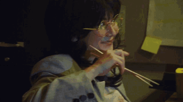 a person holding a pencil in front of a yellow sticky note that says ' a ' on it