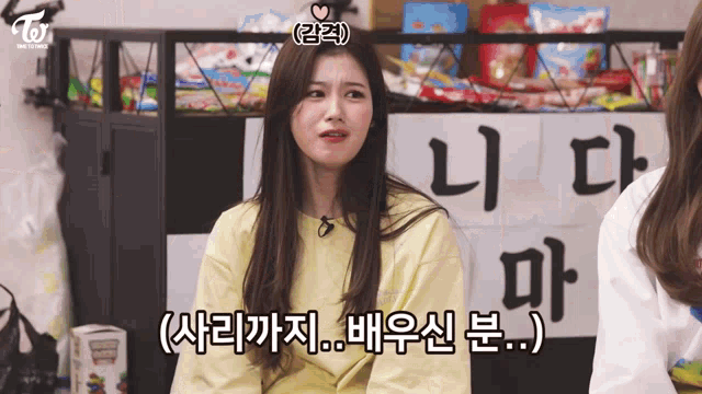 a girl in a yellow shirt is sitting in front of a sign that says twice .