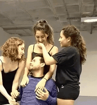 a man is surrounded by three women including one wearing a black shirt