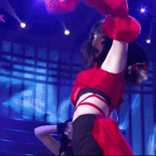 a woman in a red crop top and black shorts is dancing on a stage