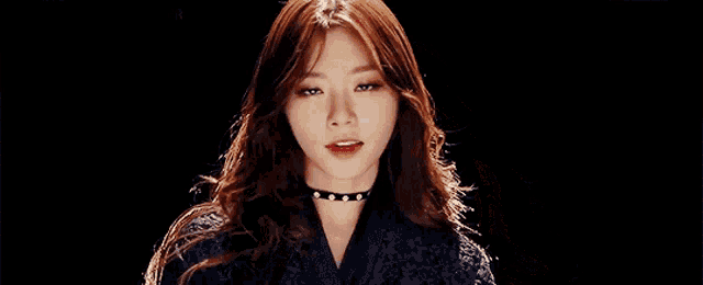 a woman in a black jacket is making a face with her hands .