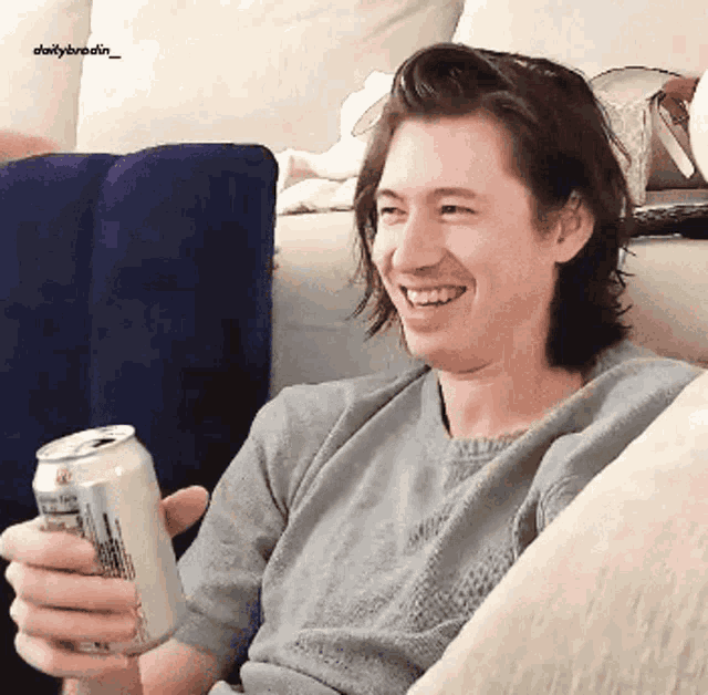 a man is sitting on a couch holding a can of coca cola