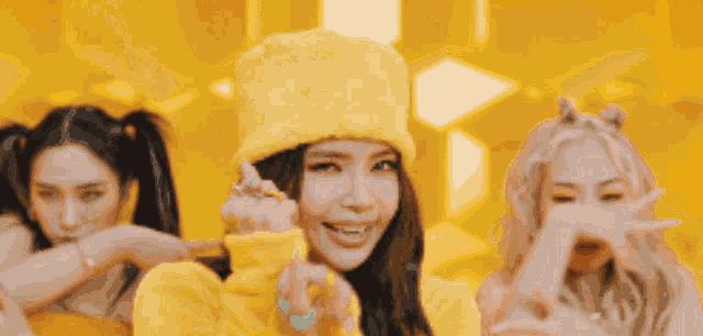 a woman in a yellow hat is dancing with two other women in yellow dresses .