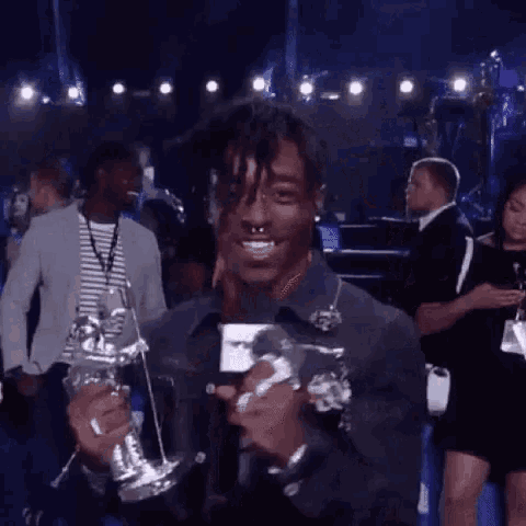 a man is holding a trophy and talking into a microphone at a concert .