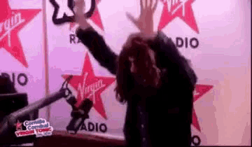 a woman is standing in front of a microphone with her arms in the air .