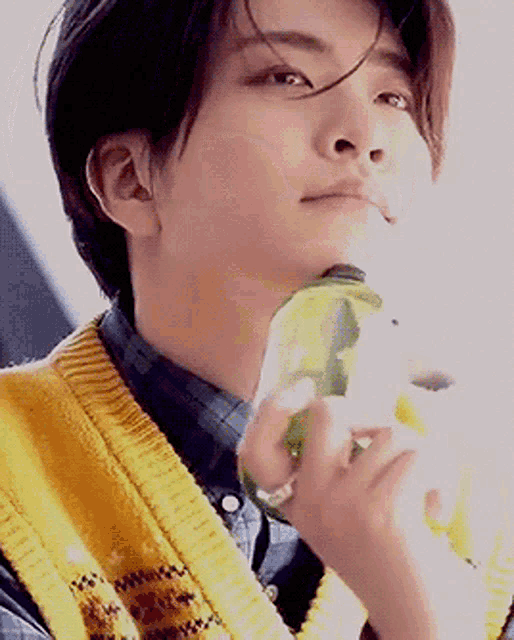a young man wearing a yellow vest is holding a bottle of water