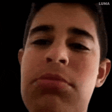 a close up of a young man 's face with a black background .