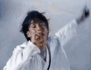 a man in a white shirt is dancing with his arms outstretched and making a funny face .
