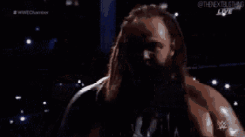 a wrestler is kneeling down in a wrestling ring with a sign that says elimination chamber