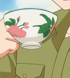 a person in a green shirt is holding a bowl with flowers on it