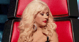 a blonde woman is sitting in a red chair and looking at the camera .