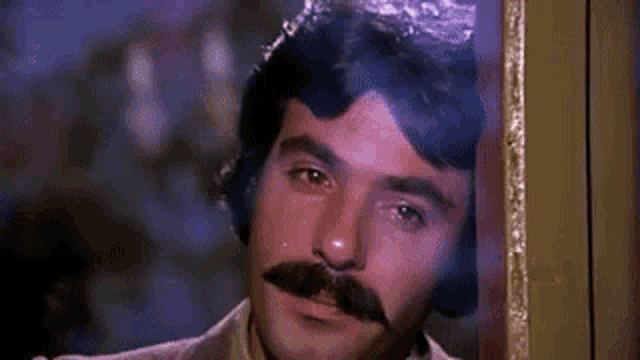 a man with a mustache is peeking out of a doorway .