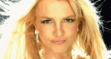 britney spears is wearing a necklace and earrings and looking at the camera .