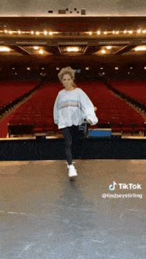 a woman is standing on a stage in an auditorium .