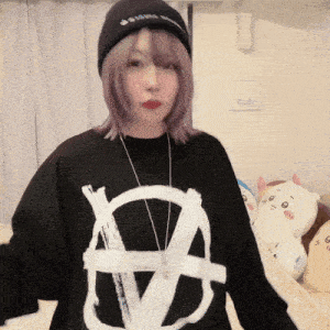 a woman with purple hair wearing a black shirt with a white symbol on it