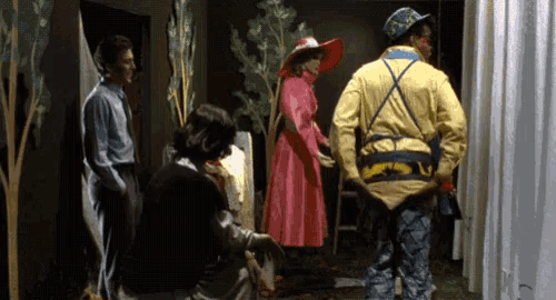 a man in a yellow jacket is standing in front of a woman in a pink dress
