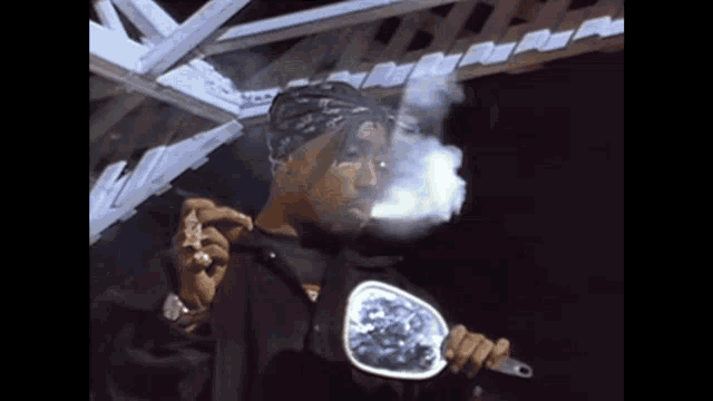 a man in a bandana is smoking a cigarette and holding a mirror
