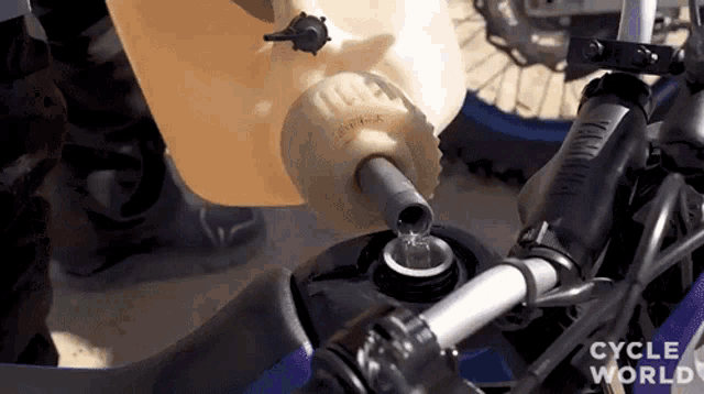 a person is pouring water into a yamaha motorcycle tank