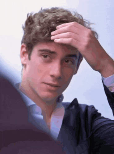 a close up of a man adjusting his hair with his hand