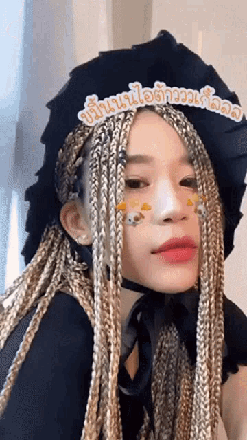 a woman with blonde braids wearing a black hat with a sticker on her face