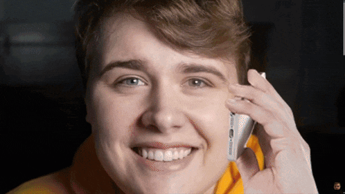 a young man is smiling while talking on a cellphone