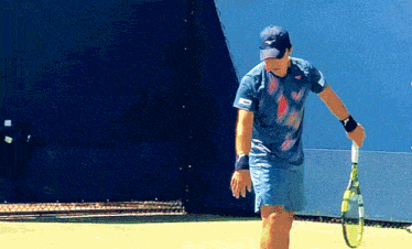 a man is holding a tennis racquet on a tennis court