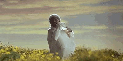 a man in a white robe is standing in a field of yellow flowers .