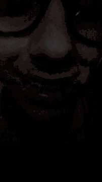 a close up of a person wearing glasses with a dark background