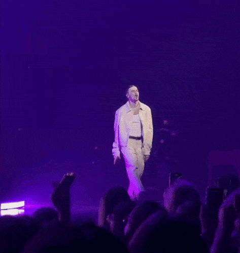 a man in a white tank top is singing into a microphone