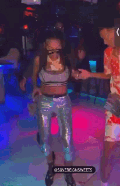 a man and a woman are dancing together in a club . the woman is wearing sunglasses .