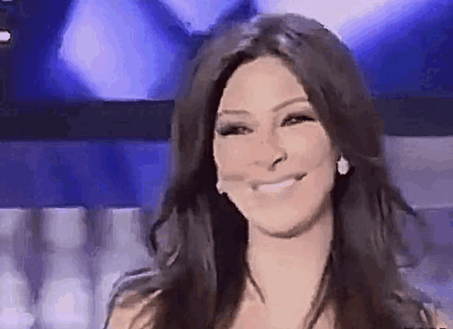 a woman is smiling and looking at the camera while wearing earrings .