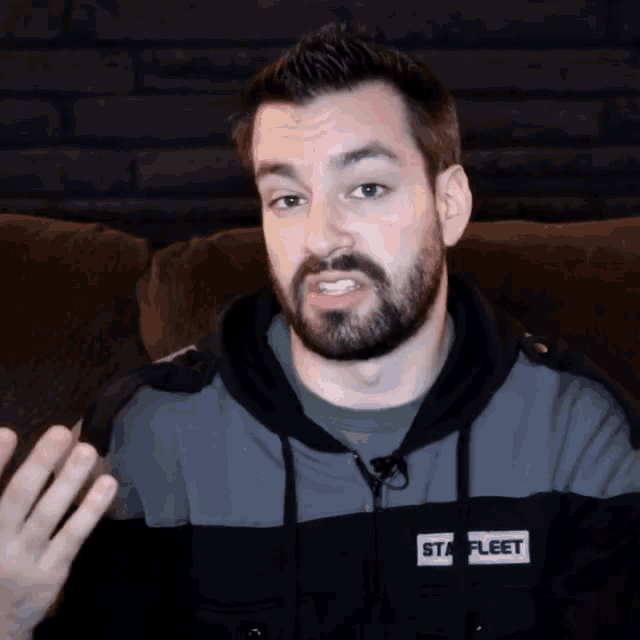 a man with a beard is wearing a black hoodie that says staff fleet