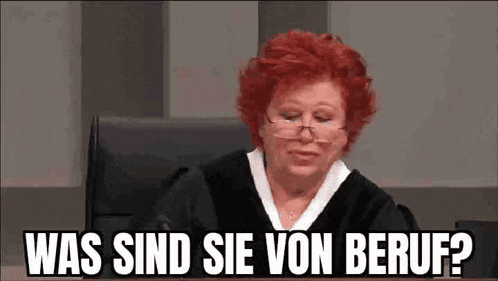 a woman with red hair and glasses is sitting in a courtroom with the words was sind sie von beruf written above her .