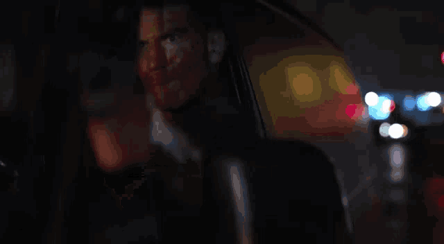 a man is pointing a gun at the camera while sitting in a car .
