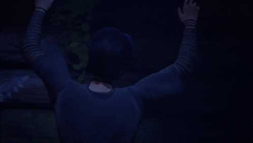 a girl with purple hair and striped sleeves is sitting in the dark with her hands outstretched
