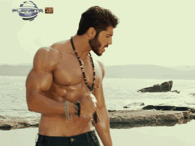 a shirtless man stands on a beach in front of a planet 4k sign