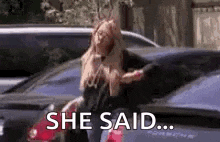 a woman is standing next to a car in a parking lot and saying she said .