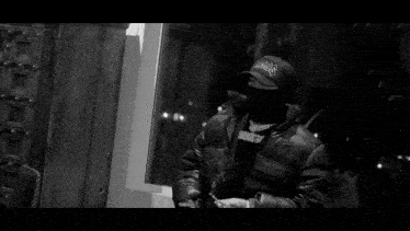 a black and white photo of a man wearing a hat that says a.r.b.s.