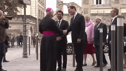 a man in a suit shakes hands with a bishop