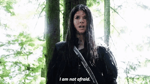a woman is standing in the woods holding a gun and saying `` i am not afraid . ''